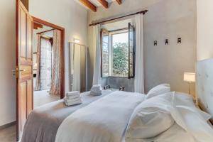 a bedroom with a large white bed and a window at U Vila in Pollença +26 photos