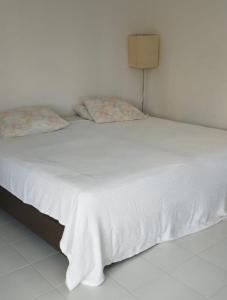 Una cama blanca con dos almohadas encima. en Edificio Arrecifes, La vida es mejor frente al mar, en Santa Marta
