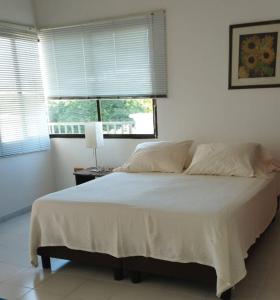 1 dormitorio con 1 cama blanca grande y ventana en Edificio Arrecifes, La vida es mejor frente al mar, en Santa Marta