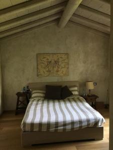 a bedroom with a bed with a striped comforter at Brick house in Sommacampagna