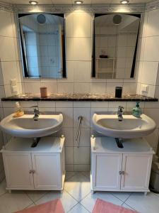 a bathroom with two sinks and two mirrors at Romantische Ferienwohnung Metzner in Remptendorf