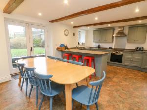 a kitchen with a wooden table and blue chairs at Clover Cottage in Kirkby Stephen