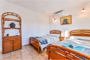 a twin bedroom with two beds and a dresser at Casa de vacaciones con piscina comunitaria in Teulada