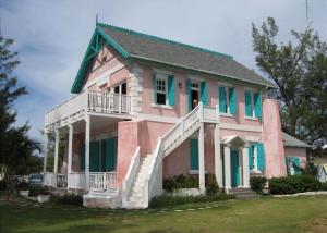 Casa rosa y verde con porche blanco en Buttonwood Reserve by Eleuthera Vacation Rentals, en James Cistern