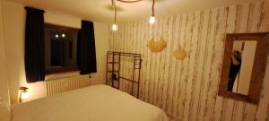 a woman standing in a bedroom with a bed and a mirror at Dikke Vriend , herberg & taverne in Chiny