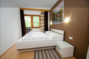 a bedroom with a large white bed and a window at OTILIA apartment in Zell am See