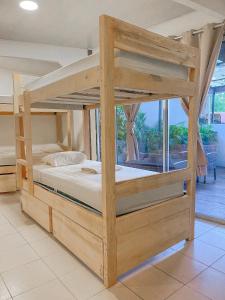 ein Etagenbett aus Holz in einem Zimmer mit Fenster in der Unterkunft El Gato Rojas Surf Hostel in Playa Santa Teresa