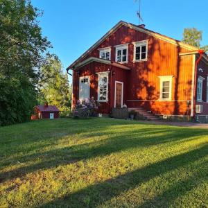 uma casa vermelha com um relvado à frente em Ainutlaatuinen huoneisto Vanhassa kyläkoulussa 