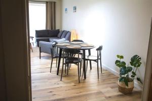 sala de estar con mesa, sillas y sofá en Ruim, lichtrijk appartement met terras in centrum en De Haan
