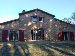 Cette maison en pierre est dotée de portes et de fenêtres rouges. dans l'établissement Les Trois Geais, aux Épesses