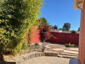 un jardín con una valla roja y una pasarela de ladrillo en The Rose Inn, en Santee