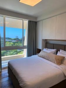 a bedroom with a large bed with a large window at neot golf kz place in Caesarea