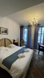 een slaapkamer met een groot bed en 2 handdoeken bij Hôtel Continental in Évian-les-Bains