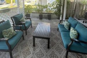 un patio con sofás azules, una mesa y un banco en Seahorse Bungalow en St Pete Beach
