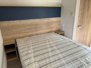 a bedroom with a bed with a wooden headboard at Leylandii 2 Bed Holiday Home in picturesque town. in Knaresborough