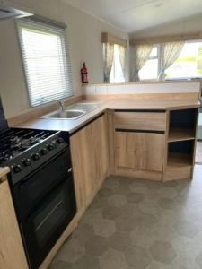 a kitchen with a stove and a sink at Leylandii 2 Bed Holiday Home in picturesque town. in Knaresborough