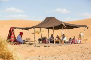 a group of people sitting under a tent in the desert at Sahara Authentic Berber Camp in Mhamid