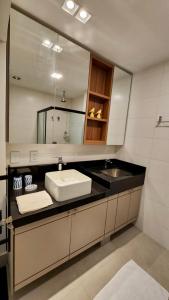 a bathroom with a sink and a mirror at Flat de Luxo c/ Quarto Privativo 21º Andar Vertigo in Campo Grande