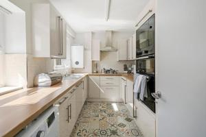 eine Küche mit weißen Schränken und einem Fliesenboden in der Unterkunft Sleek 3 bedroom in Sheffield - Sleeps 8 in Wincobank