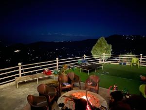 a group of people sitting around a table on a roof at Wincliff Orchard Resort in Mukteswar