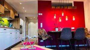 uma cozinha com uma parede vermelha e uma mesa com cadeiras em Alpenjuwel em Scheidegg