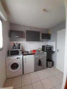 a kitchen with a washing machine and a microwave at Au feu de Berque in Cherbourg en Cotentin