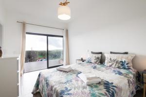 a bedroom with a bed and a large window at Casa Monte Salema in Vila do Bispo