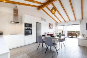 a kitchen with white cabinets and a table and chairs at Casa Monte Salema in Vila do Bispo