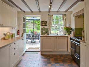 a kitchen with white cabinets and a view of a patio at Cherry Tree Cottage in Bellerby