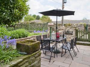a table and chairs with an umbrella in a garden at Cherry Tree Cottage in Bellerby