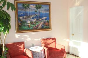 a painting on a wall with two chairs and a table at Valley Hotel in Rosemead