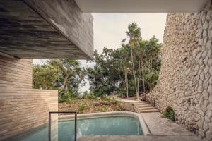 una casa con piscina junto a una pared de piedra en La Casa de la Playa by Xcaret- All Inclusive Adults Only en Playa del Carmen