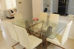 a glass dining room table with white chairs and pink flowers at Exclusive Luxury Modern Home near Robinson's Place in Manila