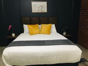 a bedroom with a large bed with yellow pillows at Black Rose Guesthouse in Soweto