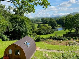 a small wooden shed in a field with a river at Garden Cottage Glamping Pod in Boncath