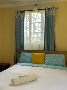 Una cama con una toalla y una ventana en Zoe Homes 1br and 2br Cottage own compound -Kericho town near Green Square mall, en Kericho