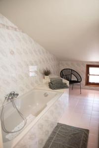 ein weißes Bad mit einer Badewanne und einem Stuhl in der Unterkunft Halte champêtre et familiale à 5 min de Tournus in LʼAbergement-de-Cuisery