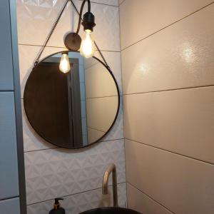 W łazience znajduje się lustro i umywalka. w obiekcie Loft city center w mieście Połtawa
