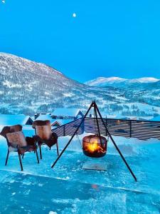 a room with a fireplace and chairs in the snow at Large and luxurious family cabin in Myrkdalen in Helgatun