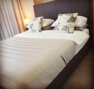 een groot bed met witte lakens en kussens bij Neot Golf, Ziv's Place in Caesarea