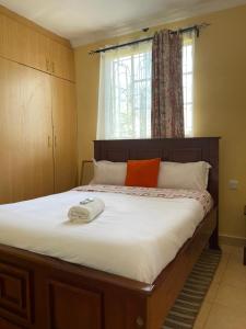 Un dormitorio con una cama grande con una almohada naranja. en Zoe Homes 1br and 2br Cottage own compound -Kericho town near Green Square mall, en Kericho