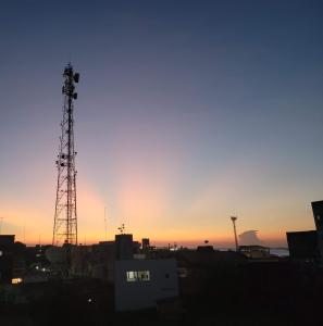a sunset over a city with two communication towers at Apartamento no centro de Santarém-PA in Santarém