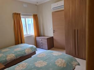 a bedroom with two beds and a dresser and a window at Sea Breeze in Żebbuġ