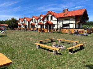 a building with benches in the grass in front of it at Słoneczne Dęby in Dębina