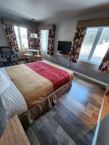 a bedroom with a large bed and a living room at Hôtel le 625 in La Malbaie