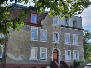an old brick building with white windows and a red door at Sea Zone Apartament przy parku in Wejherowo