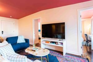 a living room with a blue couch and a flat screen tv at Blush And Bashful Germantown Two Bedroom Apartment in Louisville