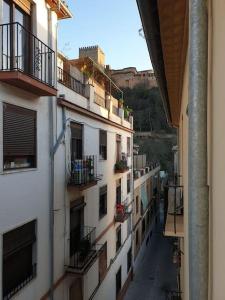 vistas a un callejón entre 2 edificios con balcón en Casita a la luz de la Alhambra II, en Granada