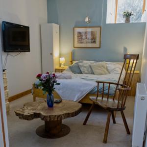 Un dormitorio con una cama y una mesa con un jarrón de flores en James John Hamilton House and backpacker hostel, en Fishguard