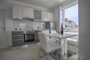 cocina con mesa, sillas blancas y ventana en Villa Laureana, en Cavtat 5 fotos más
